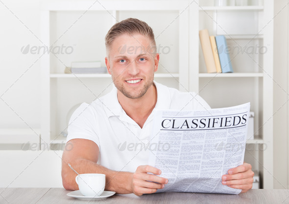 Excited man reading the classifieds (Misc) Photo Download